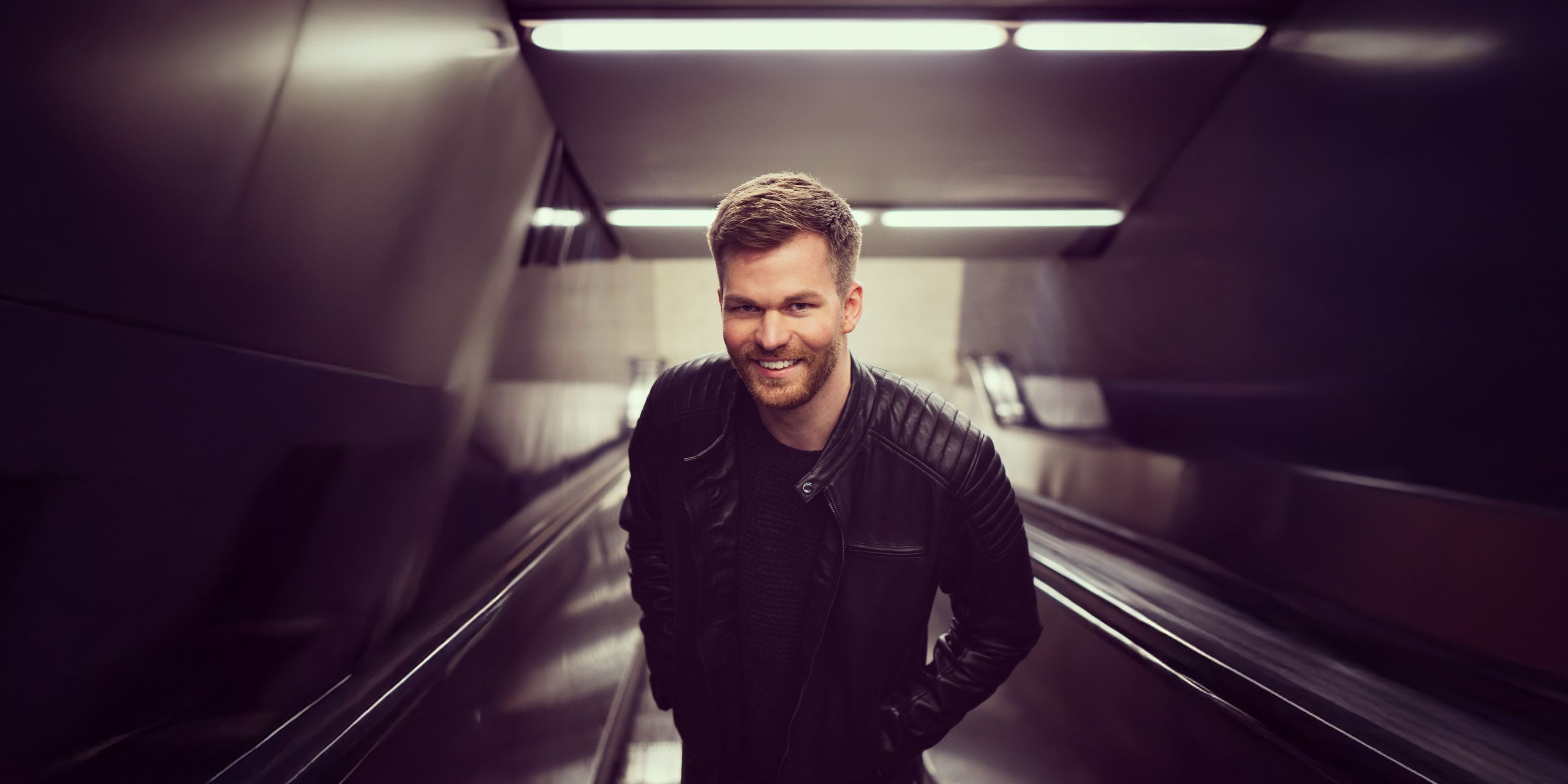 Michael Avenue standing on an escalator in a dark subway station